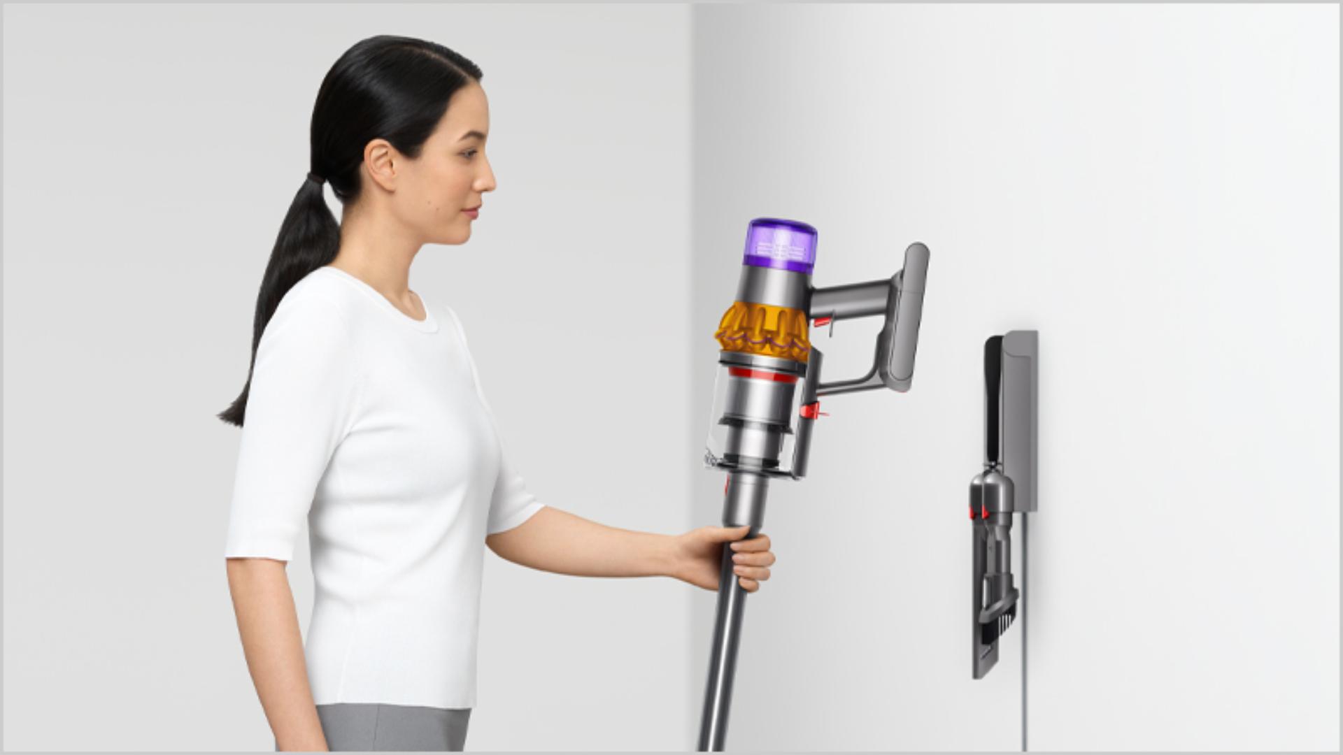 Woman placing Dyson vacuum into the wall dock