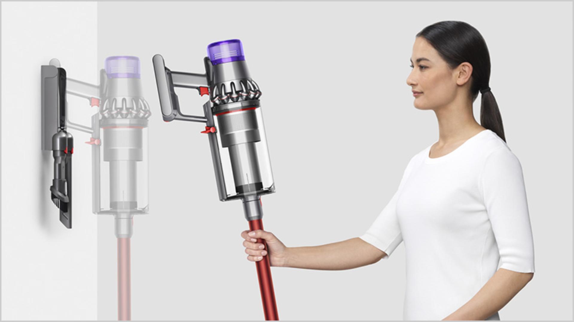 Woman placing Dyson V11 Outsize vacuum into wall charging dock