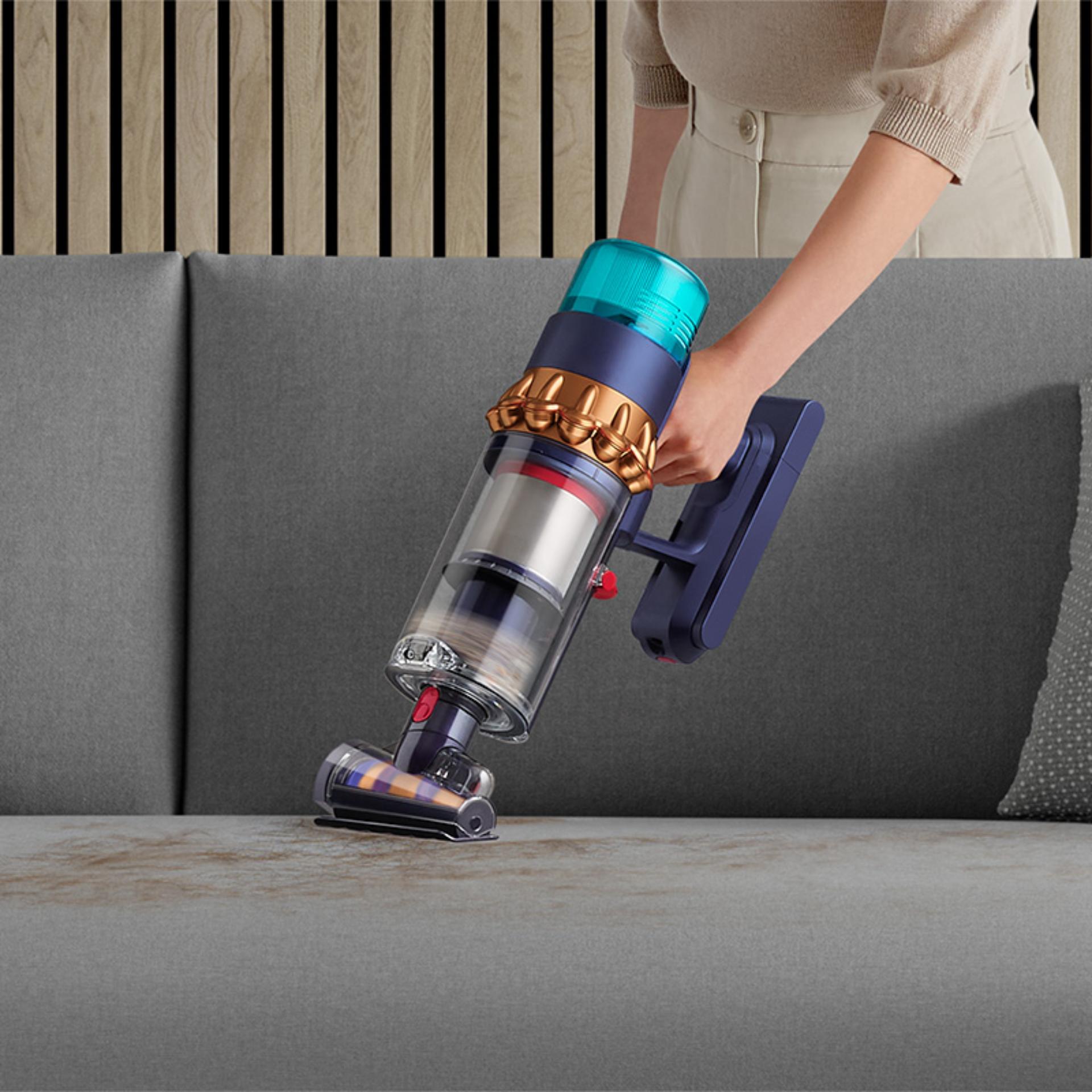 Woman vacuuming pet hair from a sofa, with the Dyson Hair screw tool.