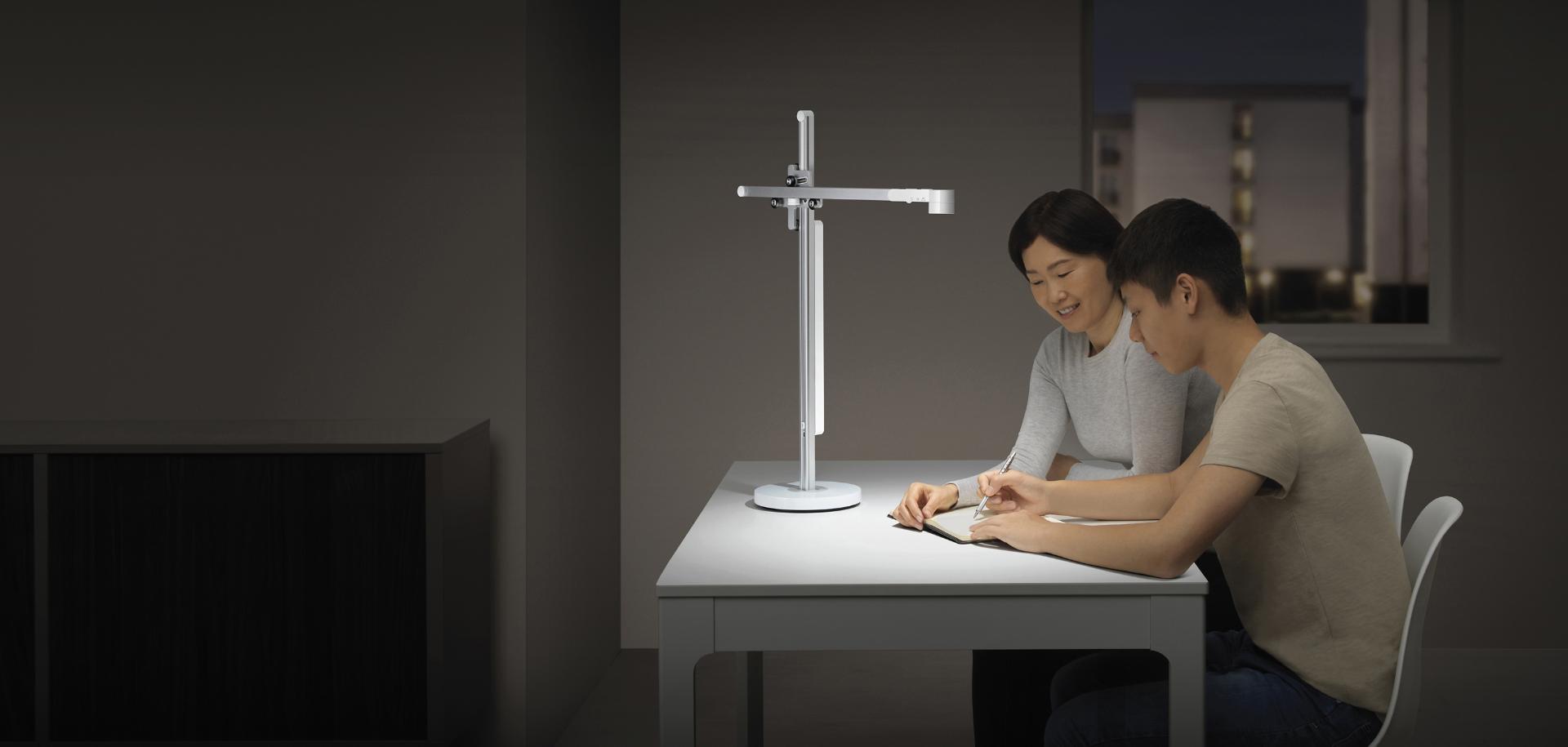 Teenager studies with his mother in powerful desk light