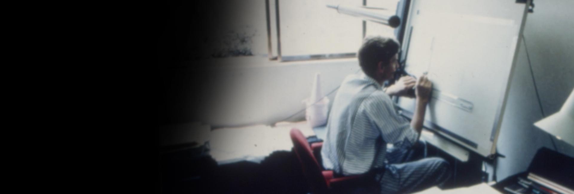 James Dyson seated in front of a technical drawing board