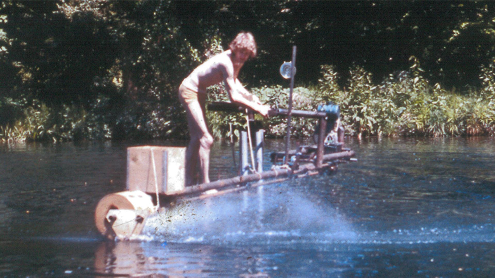 James Dyson standing with the prototype pedalo motoring through the water