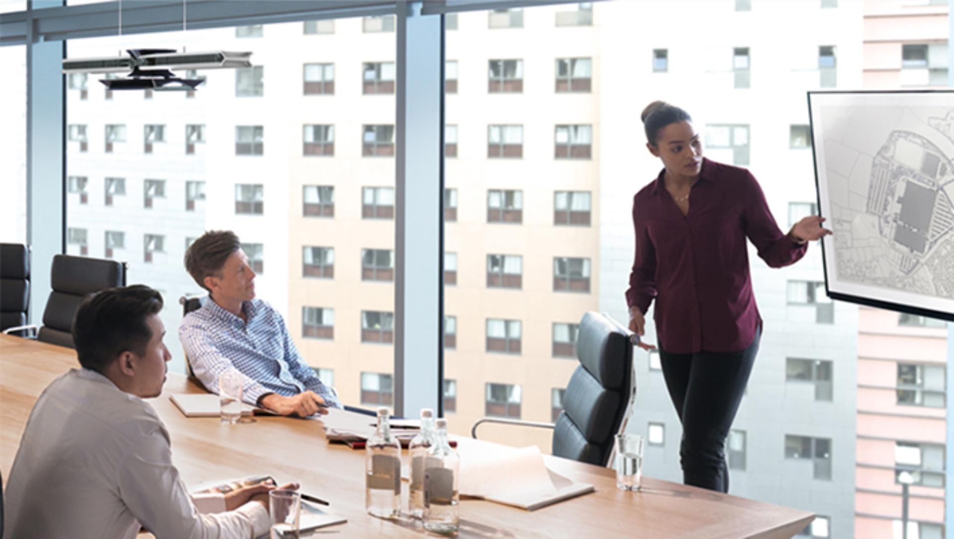 People in a meeting room looking at a graph as Cu-beam duo hangs in the back.