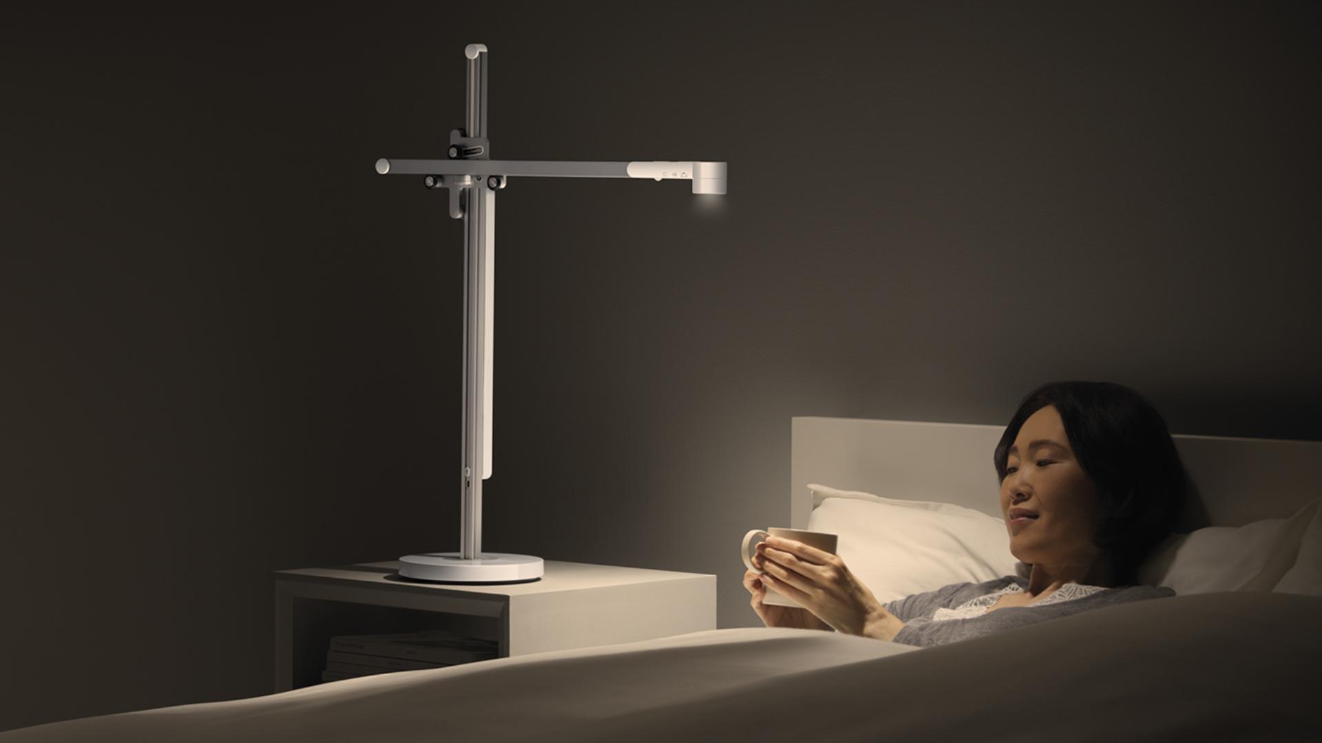 Woman reading in bed beside Dyson task light