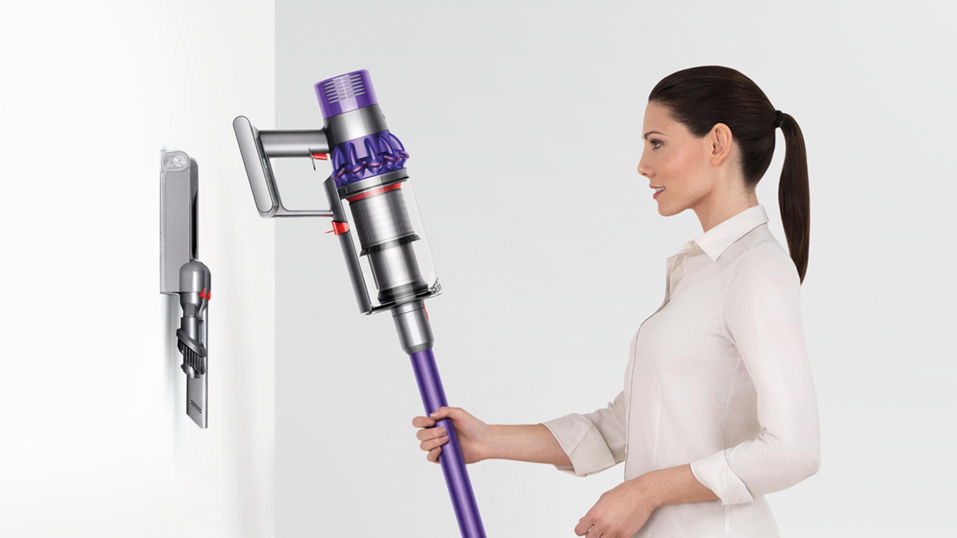 Woman droping Dyson Cyclone V10 neatly inot docking station