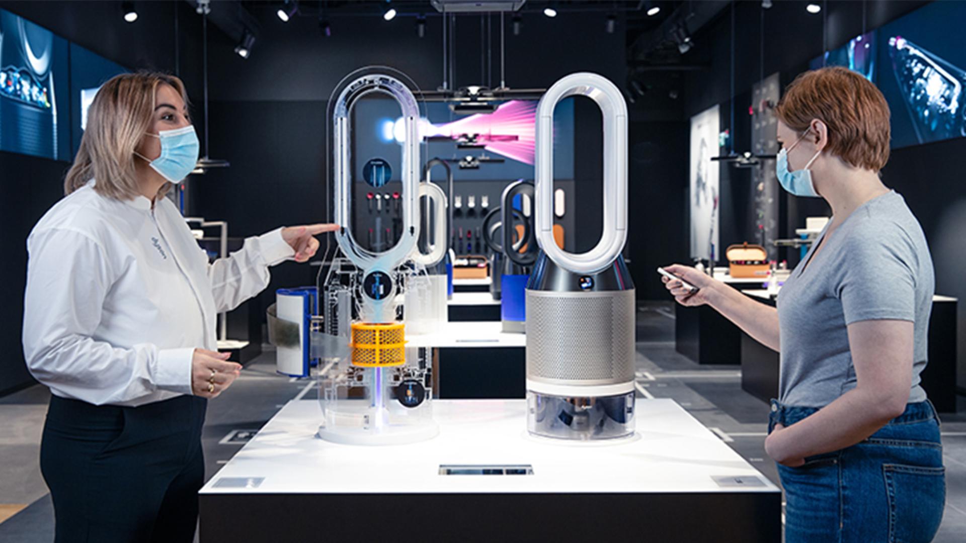 Dyson Expert talking to a customer in front of two Dyson purifiers