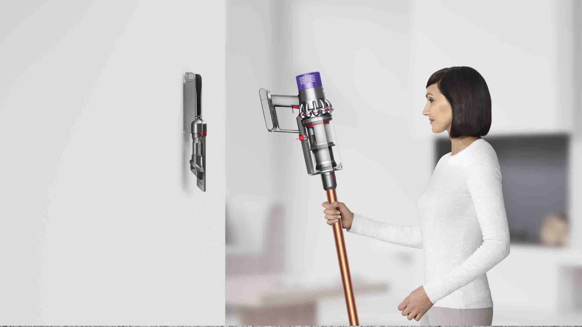 Woman droping Dyson Cyclone V10 neatly inot docking station